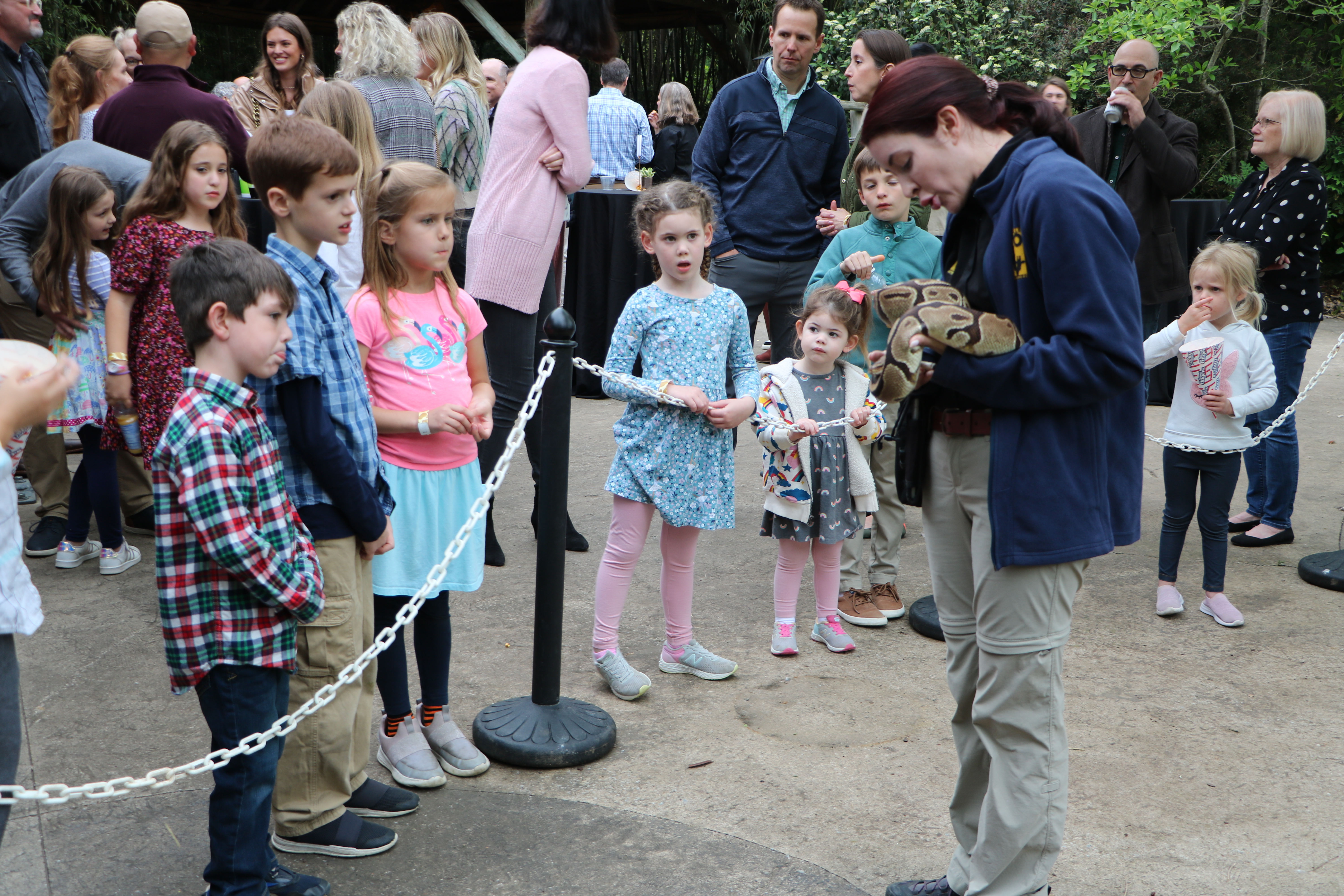 children watching a woman hold a snake